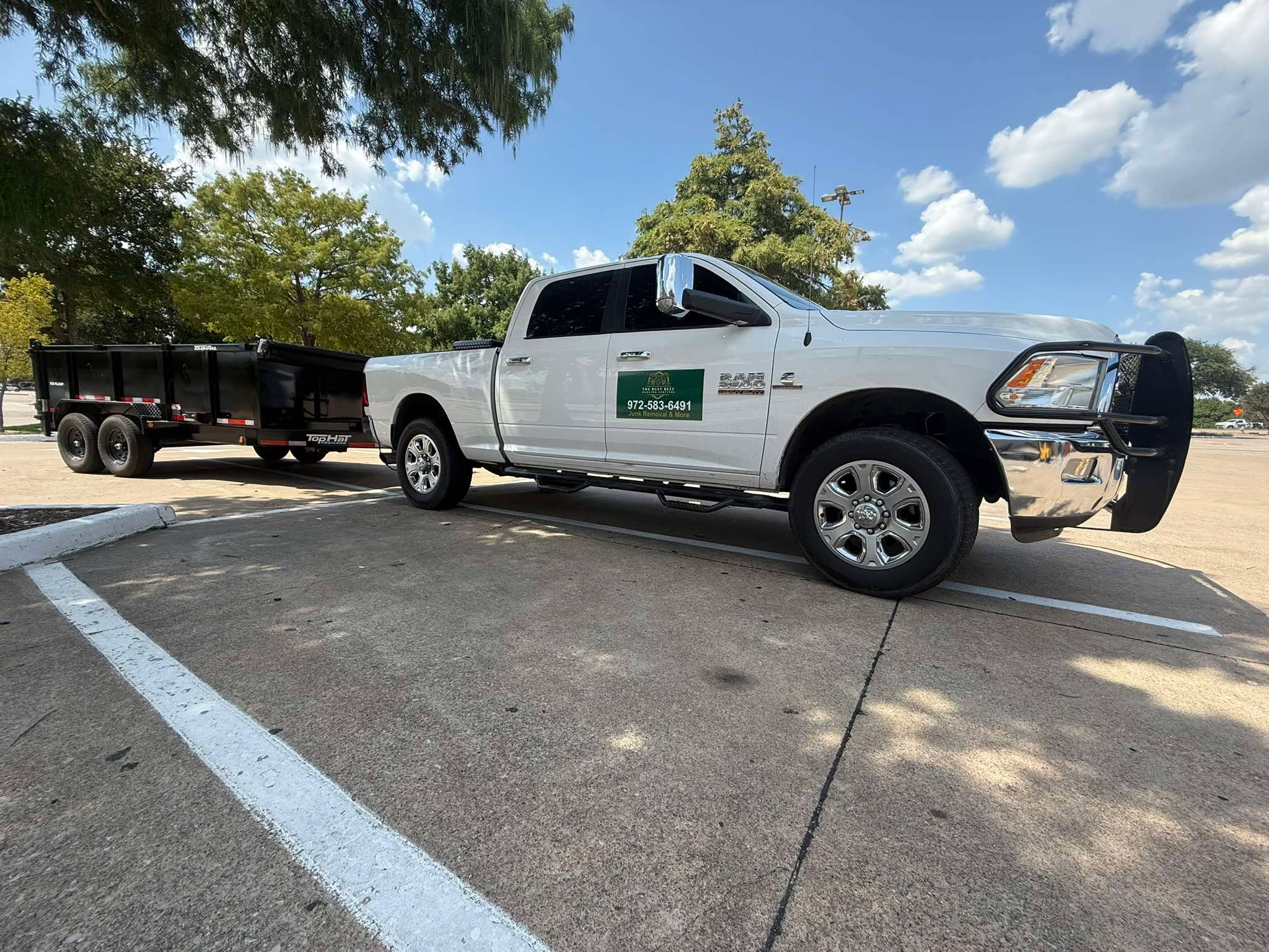 Pickup truck towing a black dump trailer in a parking lot