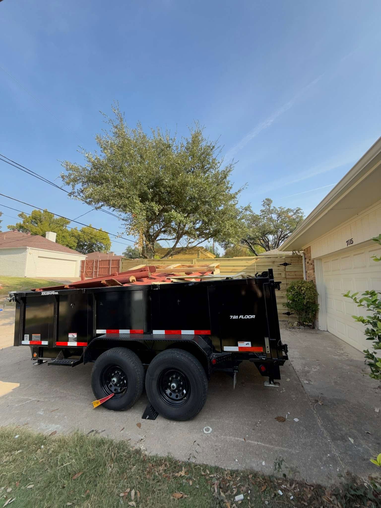 Dump trailer filled with fence and wood debris