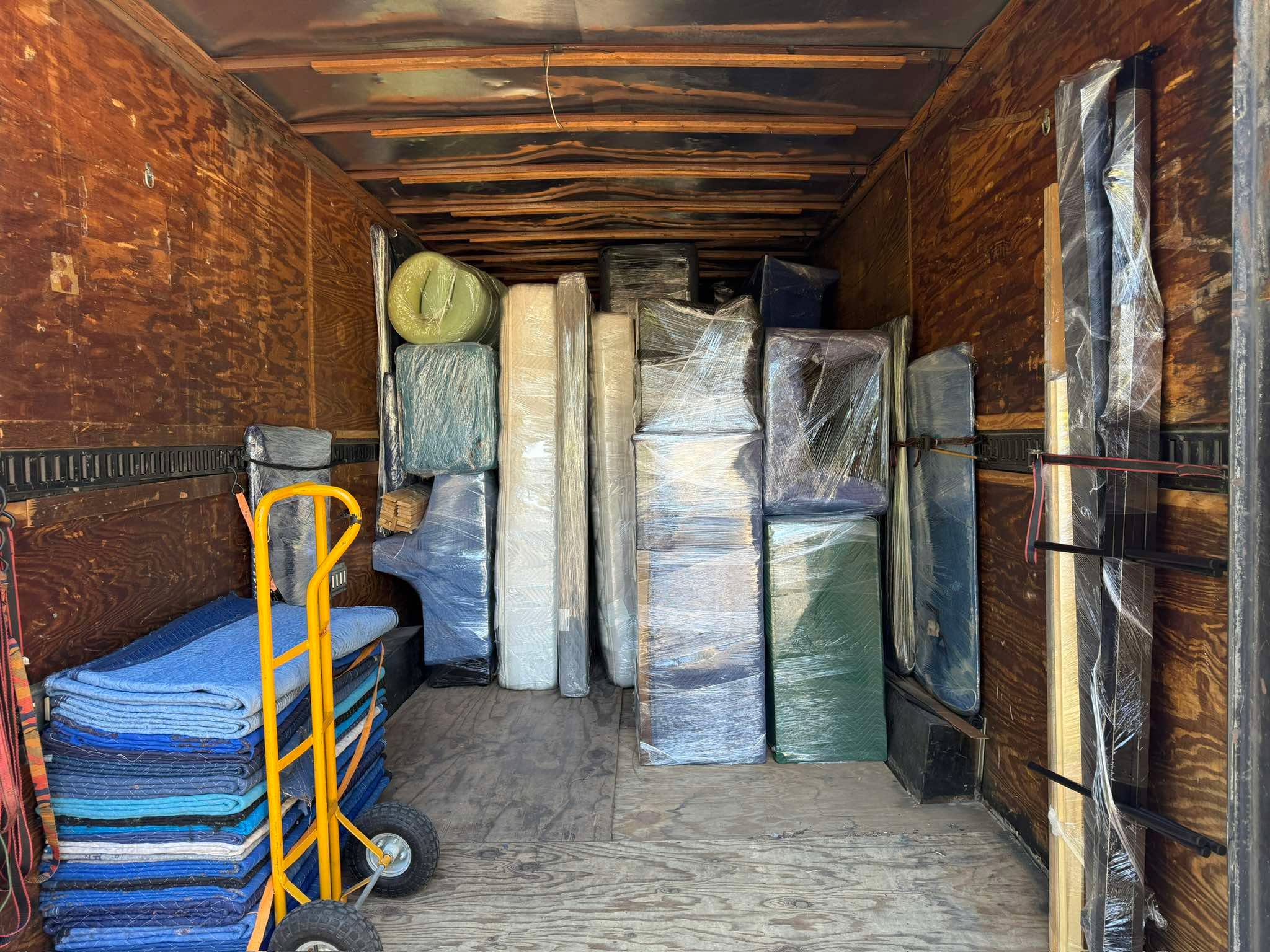 Mattresses and blanketed furniture loaded in trailer