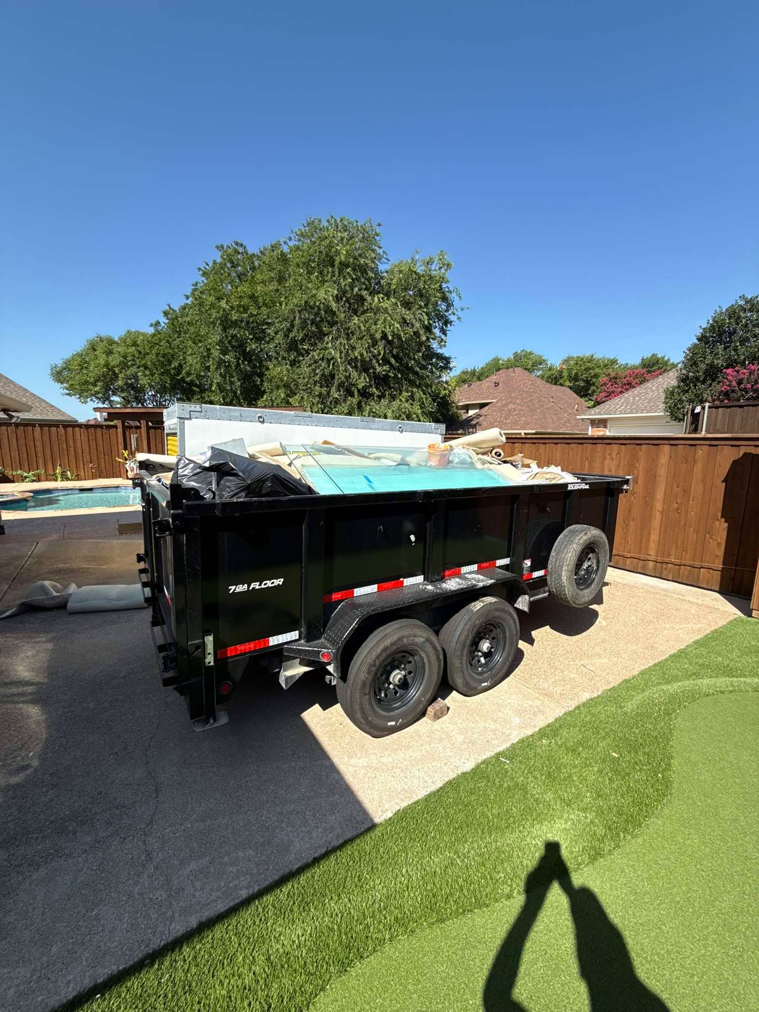 Dump trailer loaded with carpet and debris by a pool